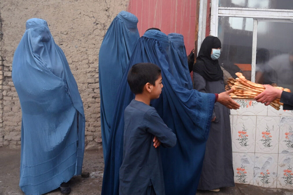 Afghan women waiting in a line to receive breads in aid outside a bakery in Kabul in January 2022.