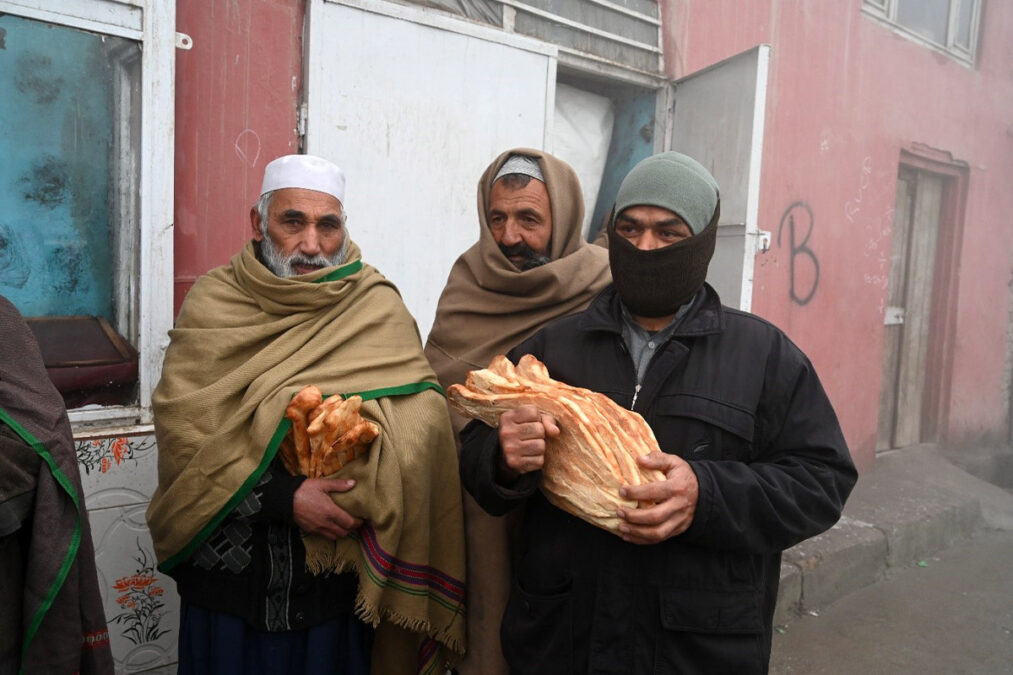 شماری از باشندگان کابل پس از گرفتن نان از سوی یک برنامه مددرسانی در کابل. حوت ۱۴۰۰.